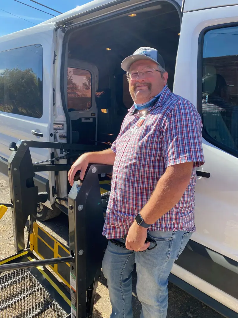 Basin Medical driver standing beside a transport van and stretcher